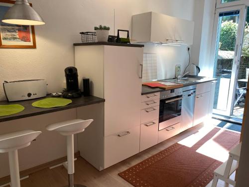 une cuisine avec des placards blancs et un comptoir avec des tabourets dans l'établissement Gehen & Fahrrad Elberfeld, à Wuppertal