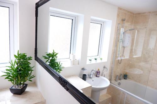 ein Bad mit einem Waschbecken, einer Dusche und einem Spiegel in der Unterkunft Comfortable cozy 4bed house nearby the hospital! in Cambridge