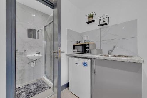 a white bathroom with a sink and a microwave at Lovely 1-Bed Studio in Feltham in Feltham