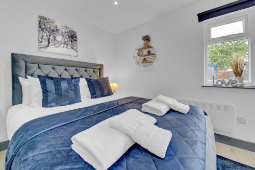 a bedroom with a blue bed with towels on it at Lovely 1-Bed Studio in Feltham in Feltham