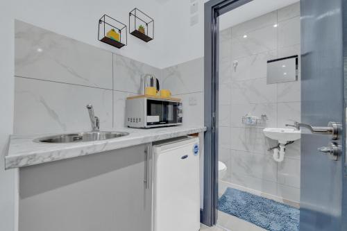 La salle de bains blanche est pourvue d'un lavabo et d'un four micro-ondes. dans l'établissement Serviced Ensuite Studio in Feltham London Heathrow, à Feltham