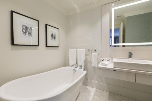 a white bathroom with a tub and a sink at Chez Truchon Bistro-Auberge in La Malbaie