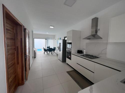 a kitchen with white cabinets and a view of the ocean at Azure 4 Bedrooms Haven Retreat: Where Tranquility Meets Turquoise Waters, Flic en Flac Mauritius in Flic-en-Flac