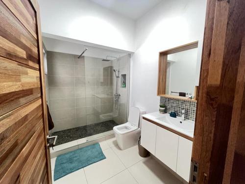 La salle de bains est pourvue de toilettes, d'un lavabo et d'une douche. dans l'établissement Azure 4 Bedrooms Haven Retreat: Where Tranquility Meets Turquoise Waters, Flic en Flac Mauritius, à Flic-en-Flac