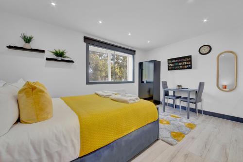 een slaapkamer met een bed met een gele deken en een bureau bij Inviting 1-Bed House in Feltham in Feltham