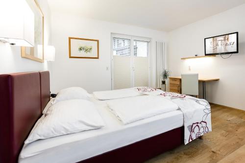 a bedroom with a large white bed and a desk at Hotel Fürst in Unterweissenbach