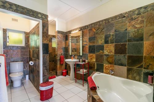 uma casa de banho com uma banheira, um WC e um lavatório. em African Breeze Guesthouse em Knysna