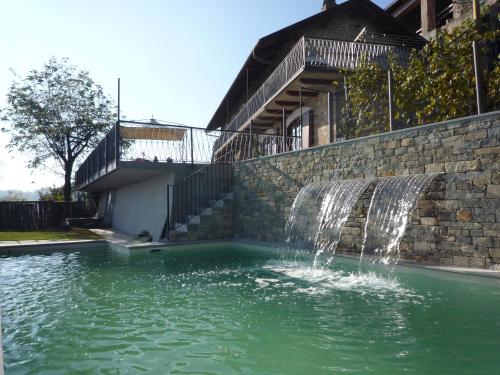 a waterfall in a swimming pool next to a building at La Vigna Del Parroco in Verduno