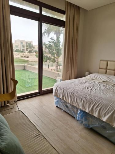 a bedroom with a bed and a large window at Hawana Salalah Lake View Villa 22 in Salalah