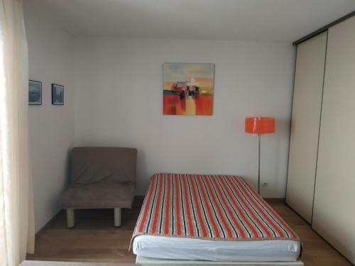 a bedroom with a bed and a chair and a painting at Studio au cœur de Valberg à proximité des pistes in Valberg