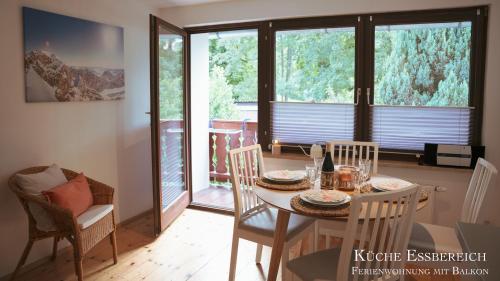 a dining room with a table and chairs and windows at Montana - Ferienwohnung am Laber in Oberammergau