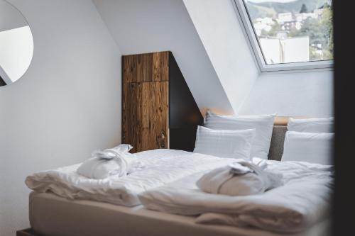 a bed with white sheets and pillows with a window at The Gast House Zell am See in Zell am See