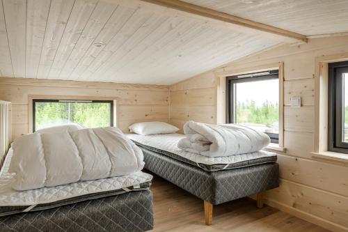 two beds in a room with two windows at Mysig liten stuga perfekt för par eller liten familj in Sälen