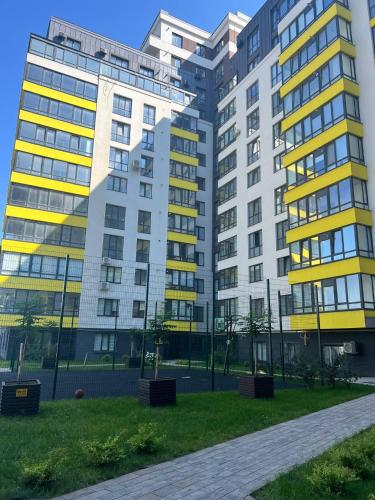 two tall buildings in a park with grass at Стильна чудова квартира в місті Тернопіль in Ternopilʼ