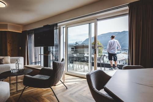 un homme debout dans une pièce avec une grande fenêtre dans l'établissement The Gast House Zell am See, à Zell am See