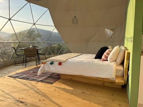 a person laying on a bed in a room with windows at Tranquil Dome - Manta's Retreat Glamping Cornereva in Cornereva