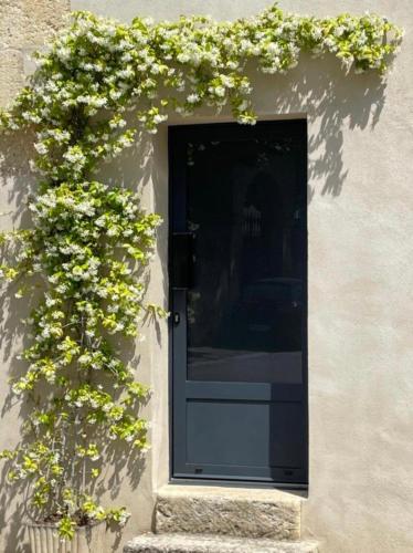 une porte noire avec des fleurs sur le côté d'un bâtiment dans l'établissement Les Cerises du Pont du Gard, à Remoulins