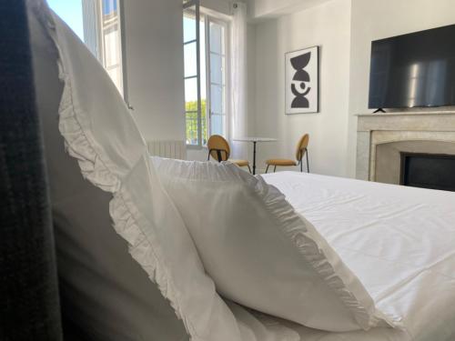 - une chambre avec un lit blanc et une cheminée dans l'établissement Maison d’hôtes Le 1853, à Narbonne