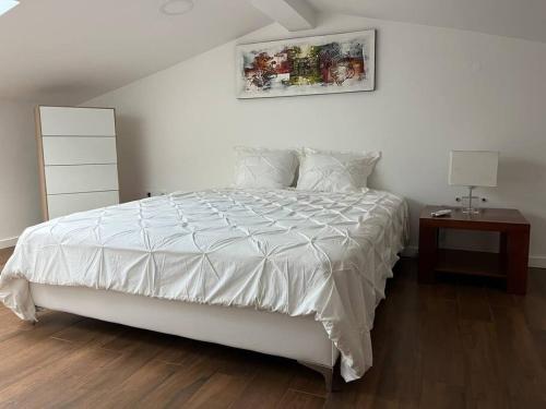 a bedroom with a large white bed and a night stand at Quinta do Carregal in Mangualde
