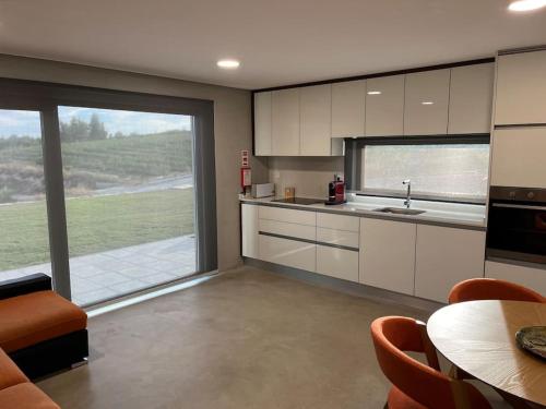 a kitchen with white cabinets and a large window at Quinta do Carregal in Mangualde