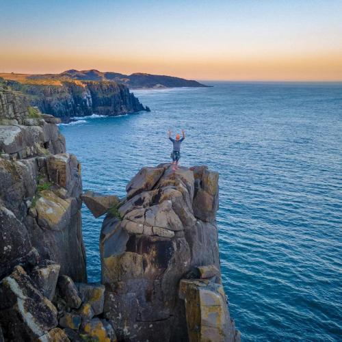 a person standing on a rock in the ocean at Hadada Self Catering Studio in Haga-Haga