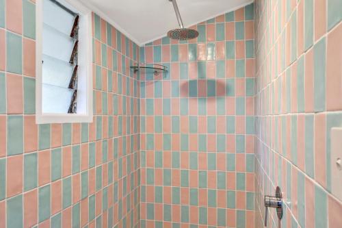 a bathroom with pink and green tiled walls and a window at Blue Waters in Point Lookout