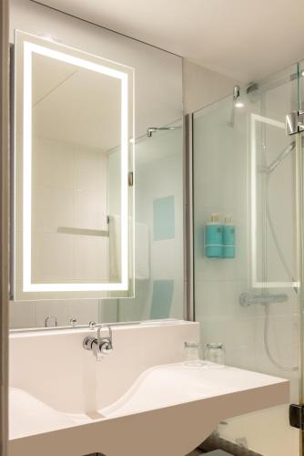 a white bathroom with a sink and a mirror at Novotel Leeds Centre in Leeds
