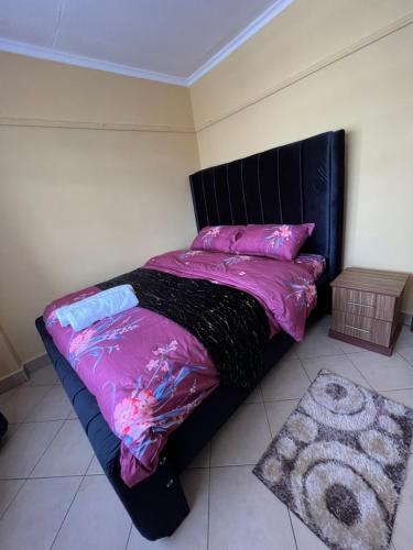 a bedroom with a bed with pink sheets and a rug at Naivasha 1BR Apartment in Naivasha