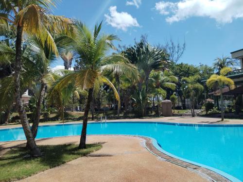 a swimming pool with palm trees in a resort at Teluk Batik Holiday Apartment in Lumut