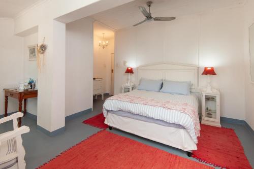 a bedroom with a bed and a red rug at The Lady Grace in Greyton
