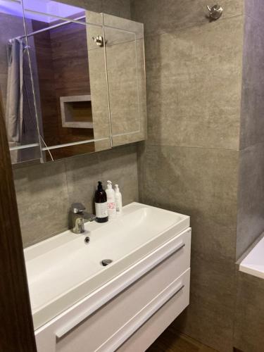 a bathroom with a white sink and a mirror at Apartament G76 in Kraków