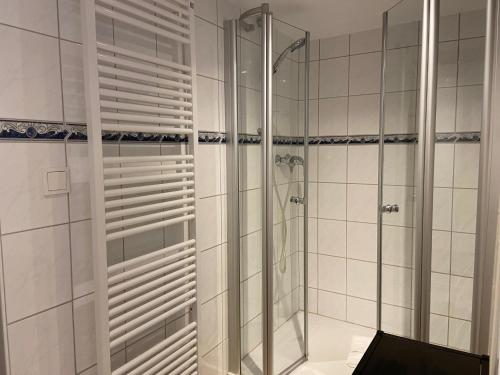 a bathroom with a glass shower with a laptop at Landhaus am Meer - Whg 5 Hilligenlei in Utersum