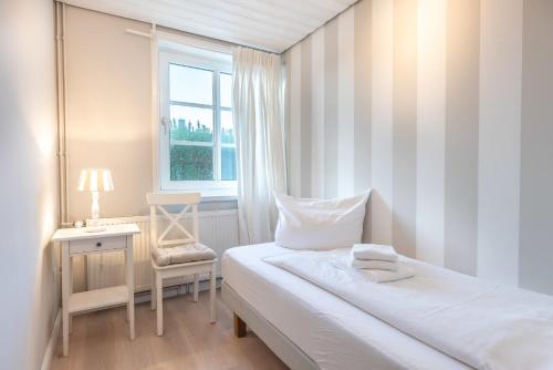 ein kleines Schlafzimmer mit einem Bett und einem Fenster in der Unterkunft Landhaus am Meer - Whg 3 Liinsand in Utersum