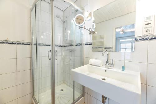 ein weißes Bad mit einem Waschbecken und einer Dusche in der Unterkunft Landhaus am Meer - Whg 3 Liinsand in Utersum
