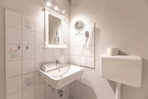 a white bathroom with a sink and a toilet at Landhaus am Meer - Whg 2 Süderaue in Utersum