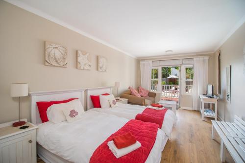 1 dormitorio con 1 cama blanca grande con mantas rojas en African Breeze Guesthouse, en Knysna