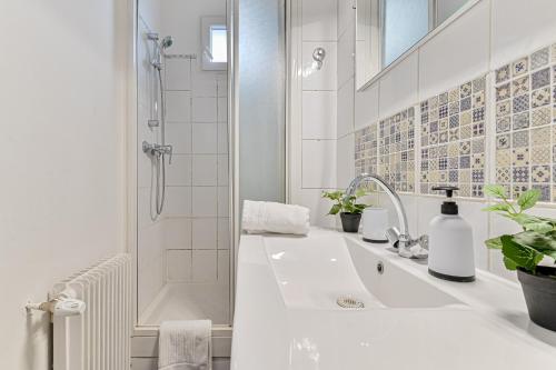 La salle de bains blanche est pourvue d'une baignoire et d'une douche. dans l'établissement Studio cosy proche Paris - 2 min RER Gentilly, à Gentilly