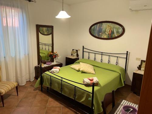 a bedroom with a green bed and a mirror at Villa Franca in Castelluccio Inferiore