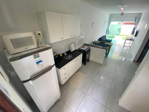 a small kitchen with a microwave and a refrigerator at Mahalo Beach Residence in Porto De Galinhas