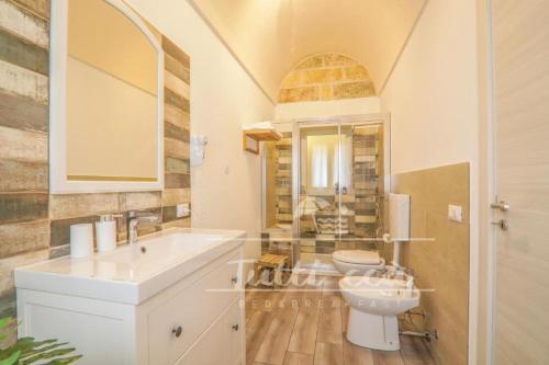 uma casa de banho branca com um lavatório e um WC em Tutti ccà Airport Rooms em Terrasini