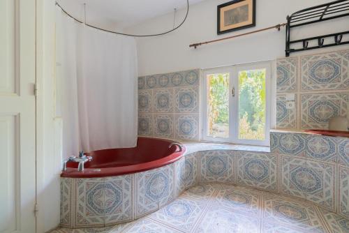 ein Bad mit einer roten Badewanne in einem Zimmer mit einem Fenster in der Unterkunft Maison Avec Piscine, Tennis, Sauna in Marsillargues