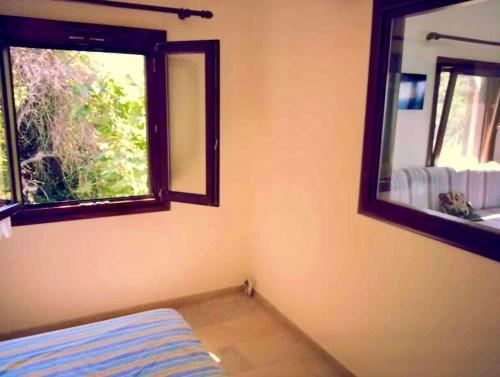 een kamer met 2 ramen en een bed en een spiegel bij Perivoli in Chorefto