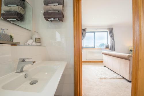 a white bathroom with a sink and a window at Seren Las, Tenby in Tenby