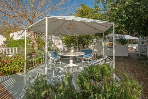 a patio with a table and chairs under an umbrella at The Lady Grace in Greyton