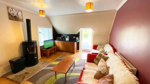 a living room with a couch and a tv at Catcune Family Suite in Gorebridge