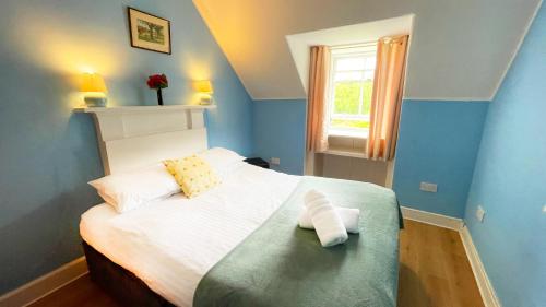 a blue bedroom with a bed with two pillows at Catcune Family Suite in Gorebridge