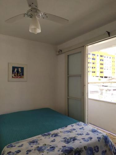 a bedroom with a bed and a sliding glass door at Apartamento 3 minutos da orla in Capão da Canoa