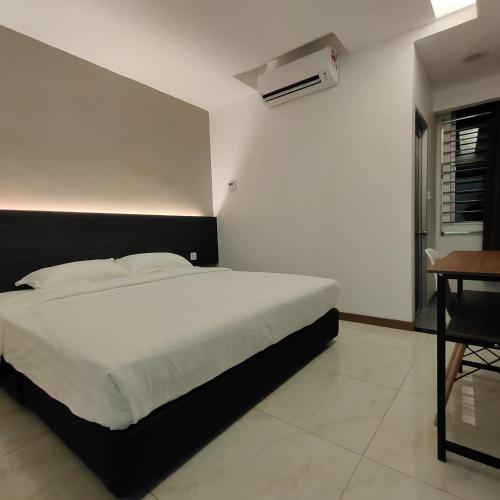 a bedroom with a white bed and a desk and a bed sidx sidx at Comfort Inn Salim in Sibu