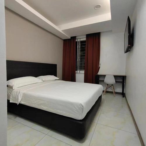 a bedroom with a large white bed and a chair at Comfort Inn Salim in Sibu