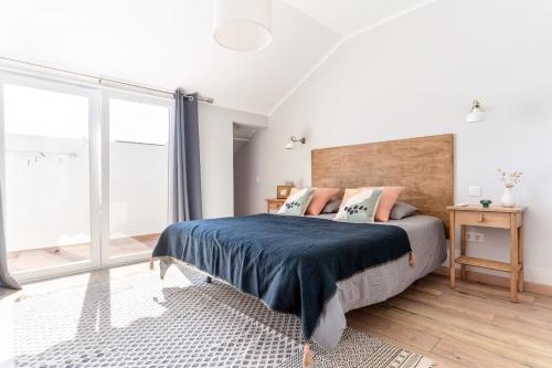 a bedroom with a bed and a large window at Windmill Escape - Areia Townhouse by Lisbeyond in Odeceixe